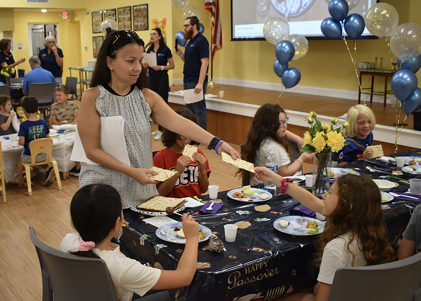 Farrah Fishman distributes a piece of matzah to 9-year-old Sasha Leopold