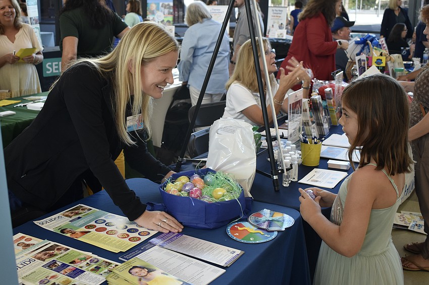 Erin Browne, a Sarasota speech therapist for Johns Hopkins All Children's Hospital, offers Easter eggs to 8-year-old Osselyn Hart.