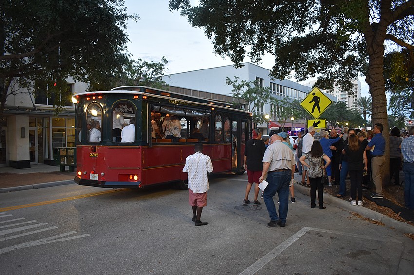 Walkers step off a trolley in front of Regal Hollywood.