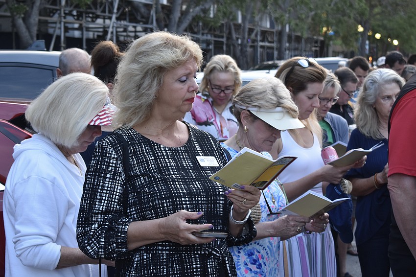 Pastor Linette McClelland of Center of Hope Church reads her event program while listening to a speaker.