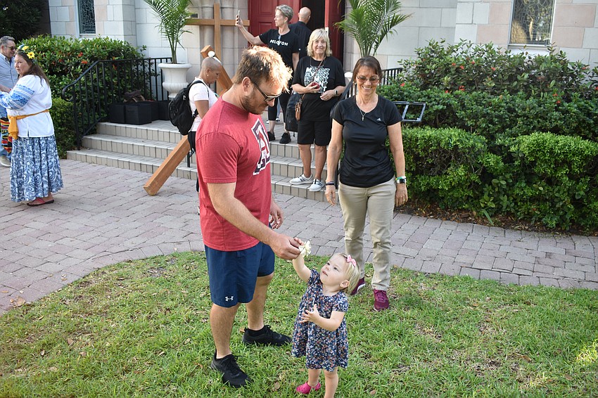 After the walk, Reed Bauer receives a flower from 2-year-old Anna Bauer, as Beth Cave watches.