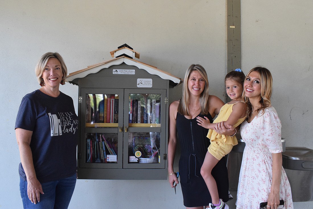 Arbor Grande's Elizabeth Henderson, who is the founder of the Little Free Library Club, Country Club East's Arielle Monserez and her 4-year-old daughter Millie Monserez and Tampa's Katerina Farese cut the ribbon on the library in April. It burned in the pavilion fire.