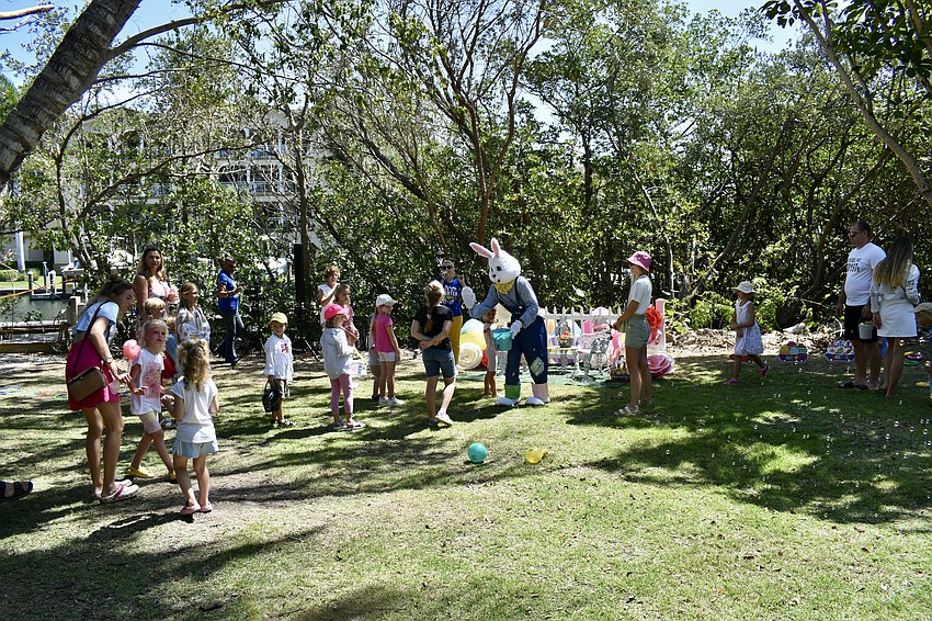 The children gather around the lawn to meet the Easter Bunny and play games.