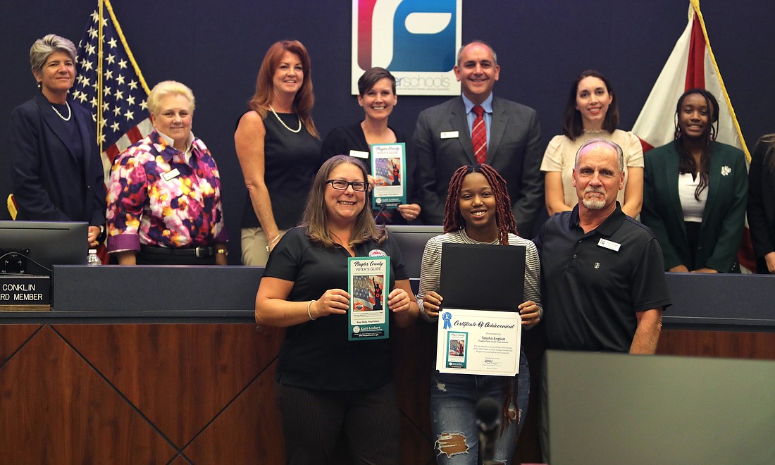 Voter's Guide contest winner Talafia English (front row center) with Flagler County Supervisor of Elections Kaiti Lenhart (left), holding English's winning cover design; FPC photography and graphic design instructor Ed Beckett (right); and Superintendent Cathy Mittelstadt and the School Board (back row). Photo by Brent Woronoff