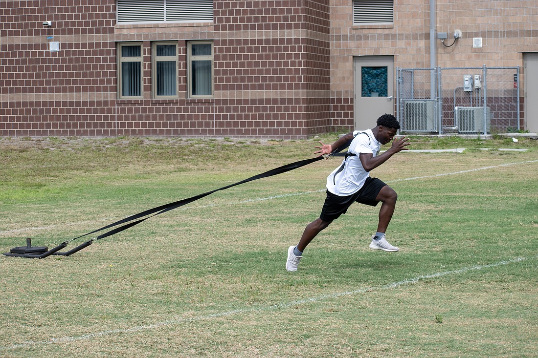 Booker High junior Jayson Evans sprints with a weighted sled during an April 11 track and field training session.