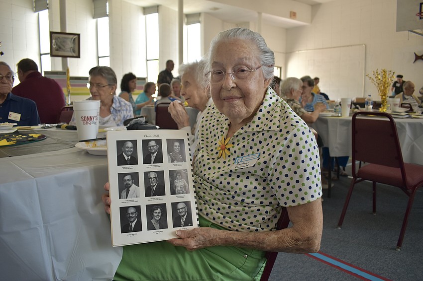 97-year-old Pauline Everett holds a staff directory from when she first became involved with the church in about 1969 as a secretary, with her photo included in the upper right corner.