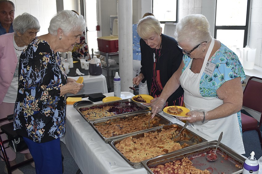 Marcy Thurlow receives food from Beatty Shipley and Diane Freestone.