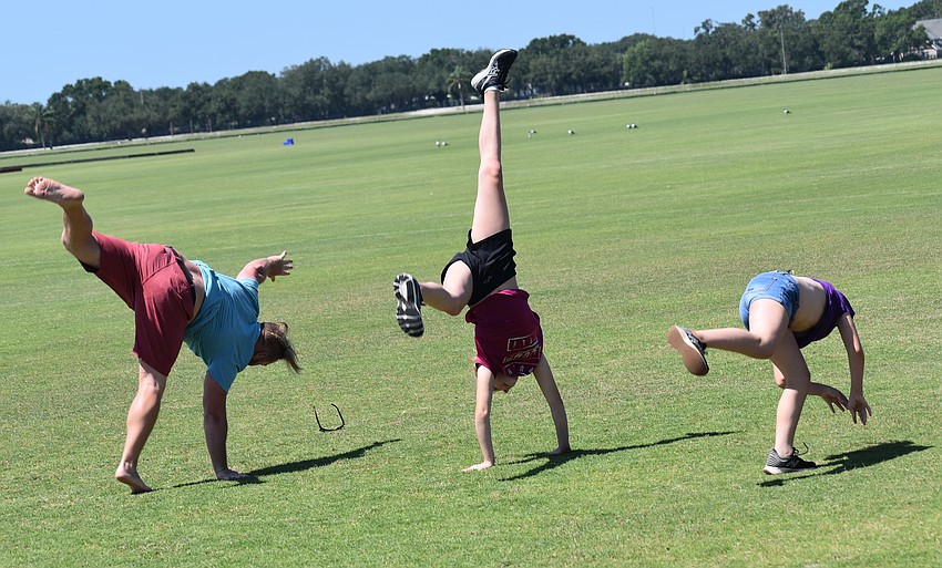 Scott Benson, Olivia Rushmore and Kiernan Lemmons warm up for polo with a cartwheel race at the Sarasota Polo Club.
