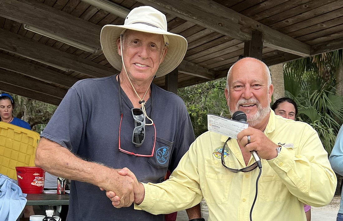 Gene Van Dorpe Sr., left, winner in the redfish category at the Flagler Sportfishing Club's 27th Inshore Spring Classic Tournament, accepts a check and congratulations from Capt. Chris Davy of Southern Fried Charters.