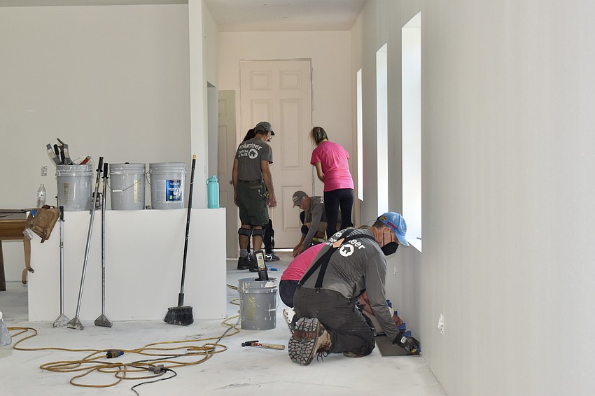 Volunteers install flooring.