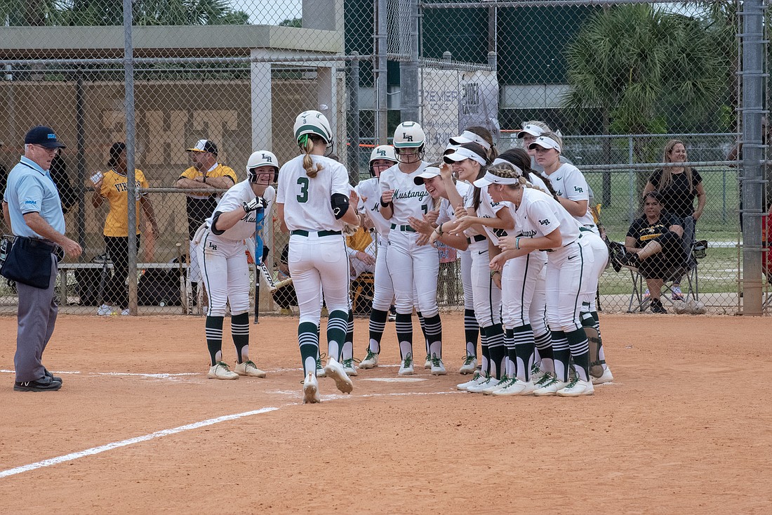 The Mustangs greet senior Cassidy McLellan at home plate after a leadoff home run against Bishop Verot.