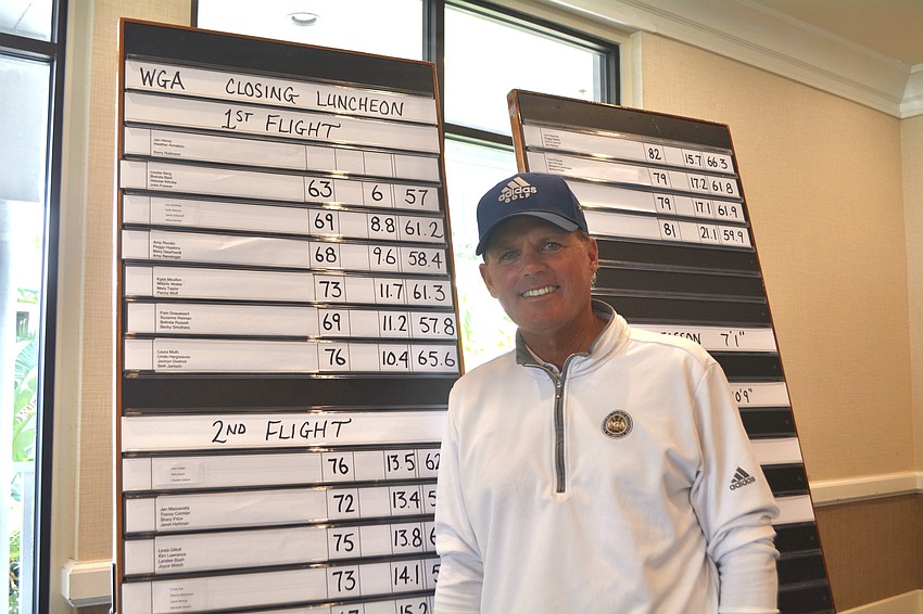 Terry O'Hara, director of golf, stands next to the day's results at the WGA luncheon.