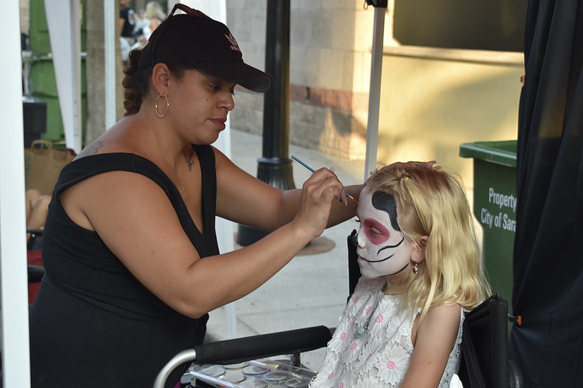 Lesly Soto of La Makeup Artistry paints the face of 9-year-old Grace Dendy at the Circo event