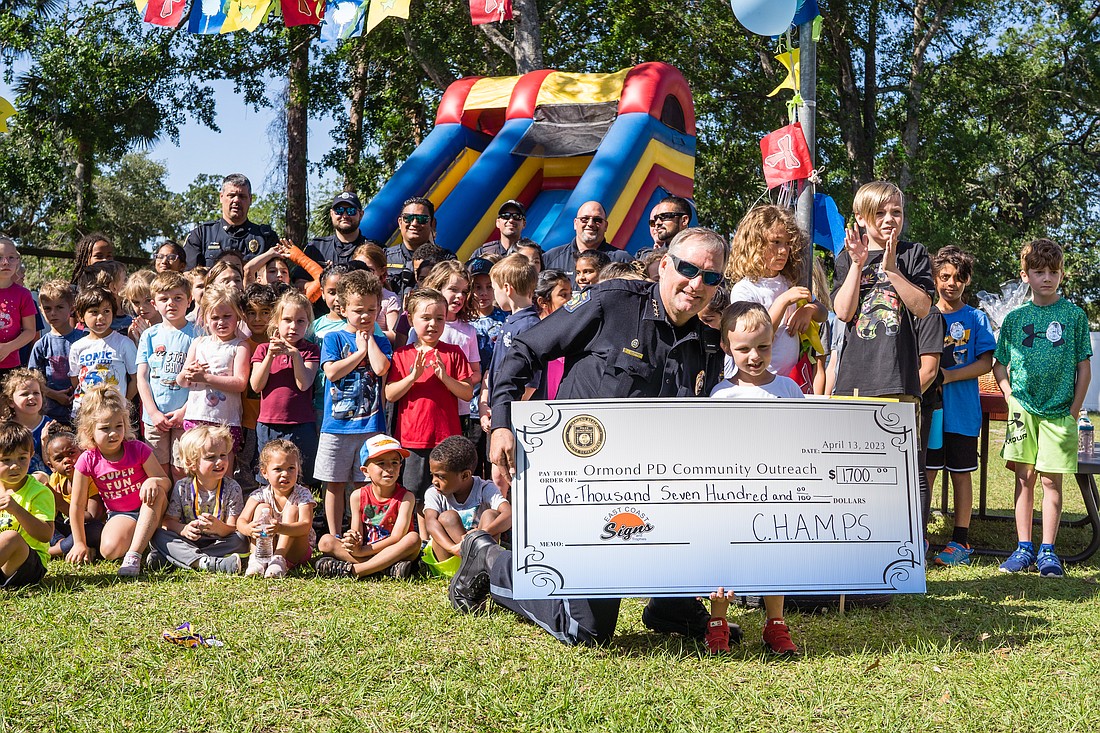 Ormond Beach Police Chief Jesse Godfrey receives a check from top fundraiser Finley Thornton, on behalf of the Children's House. Photo courtesy of Sara Price/Upwell Photography