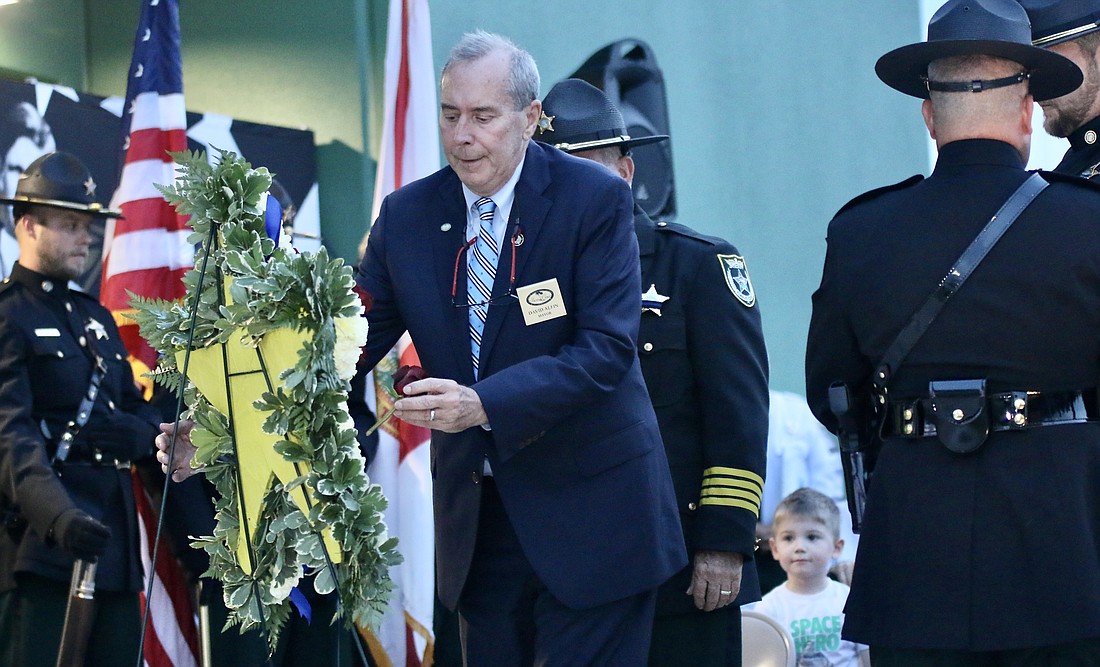 Palm Coast Mayor David Alfin places a rose in honor of his son, Daniel Alfin, who died in the line of duty in 2021. Photo by Sierra Williams.