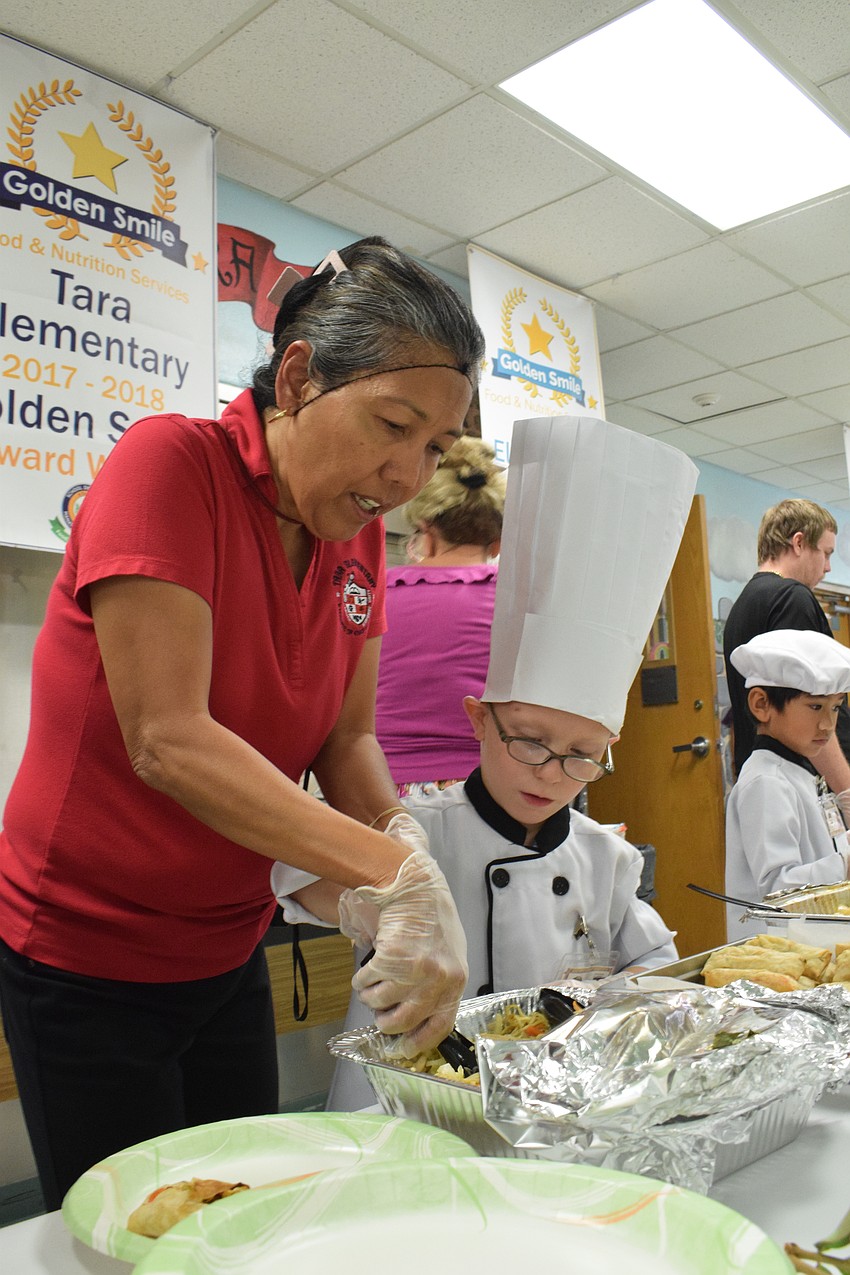 Kindergarten teacher Josephine Johnson helps kindergartner and chef Blake Coleman serve chicken canton noodles with vegetables.