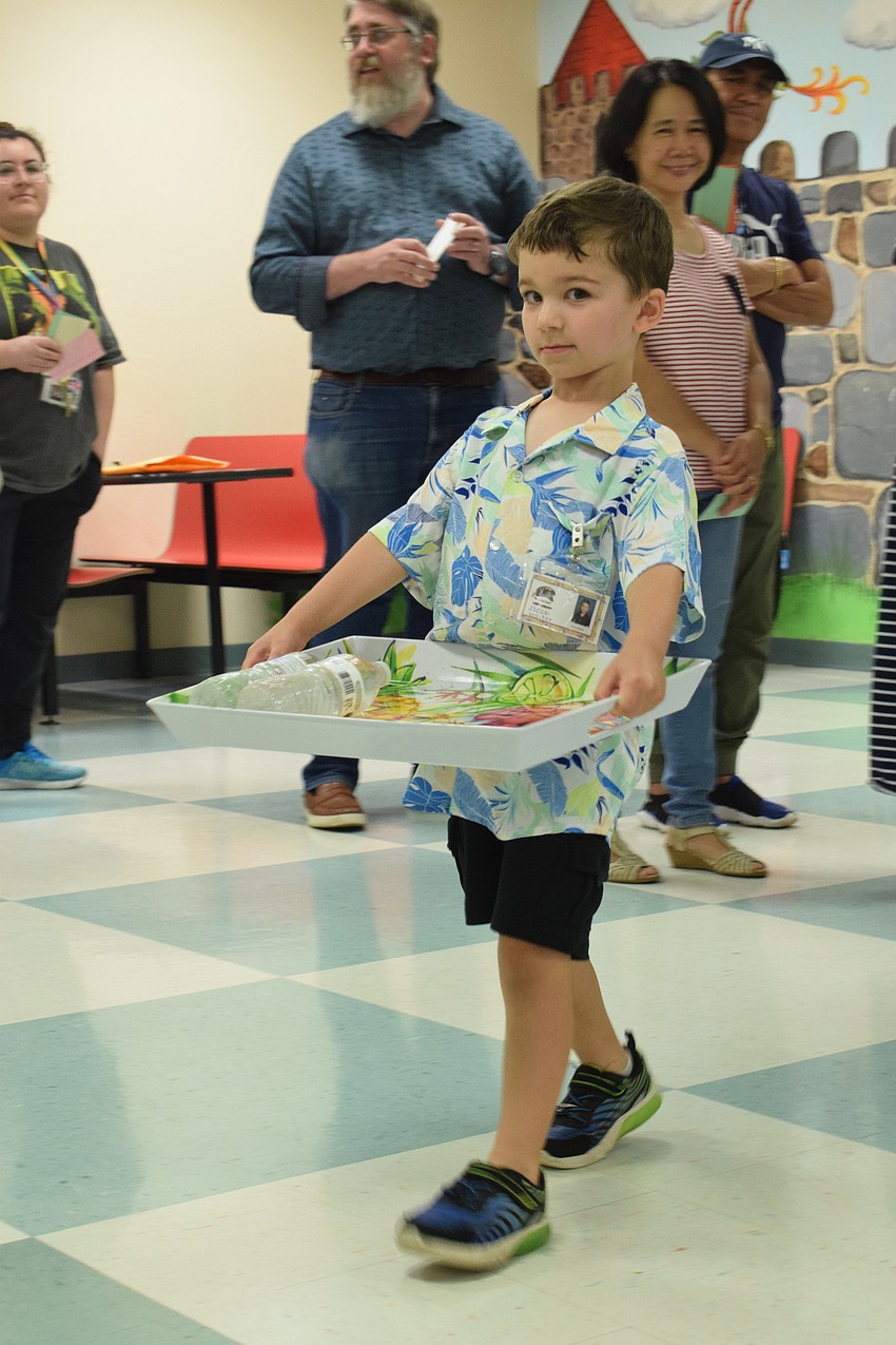 Kindergartner Jacob Bowman carefully carries water to serve to customers of the Banana Leaf Restaurant.