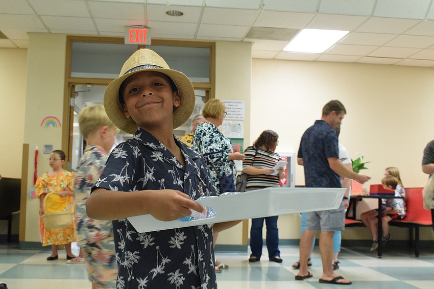 Kindergartner Cason Collier is beaming with pride as he serves water to customers.