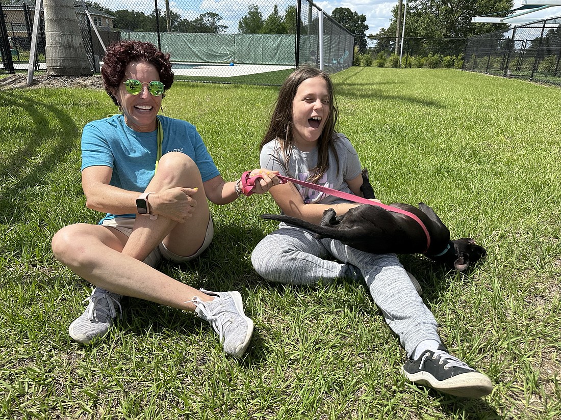 Temple Emanu-El Mitzvah Day project captain Merryl Koven and Alexandra Marcus laugh together as they play with an adoptable dog at Nate's Honor Animal Rescue.