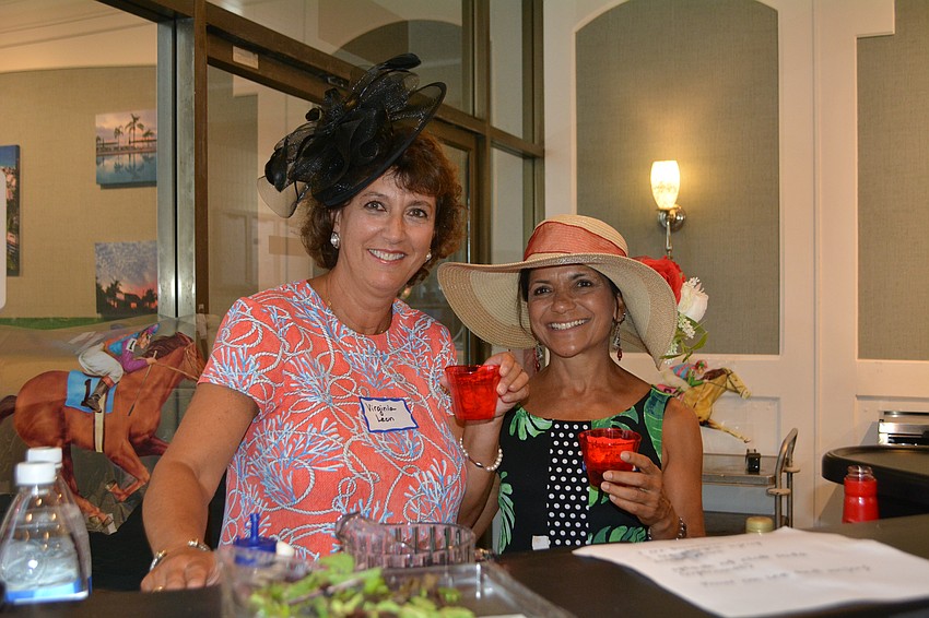Virginia Leon and Kakali Banerjee, event coordinators, hold up their Mint Juleps at the Longboat Harbour Condominium's Kentucky Derby Party.