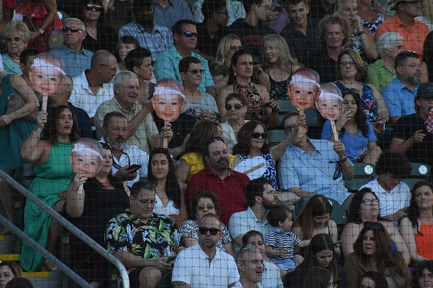 Families hold up cutouts of a graduate from when she was a baby.