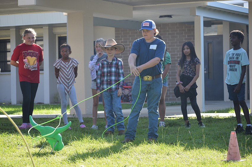 Gene Witt Elementary School students watch carefully as Clayton Reagan with Reagan Ranch demonstrates how to use a lasso.