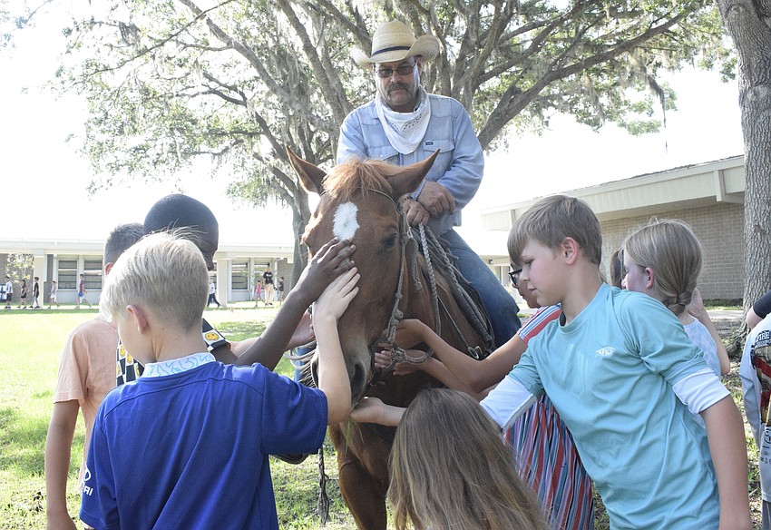 Brian Fielder keeps Lizzie, a horse, in place while Gene Witt Elementary School students pet her.