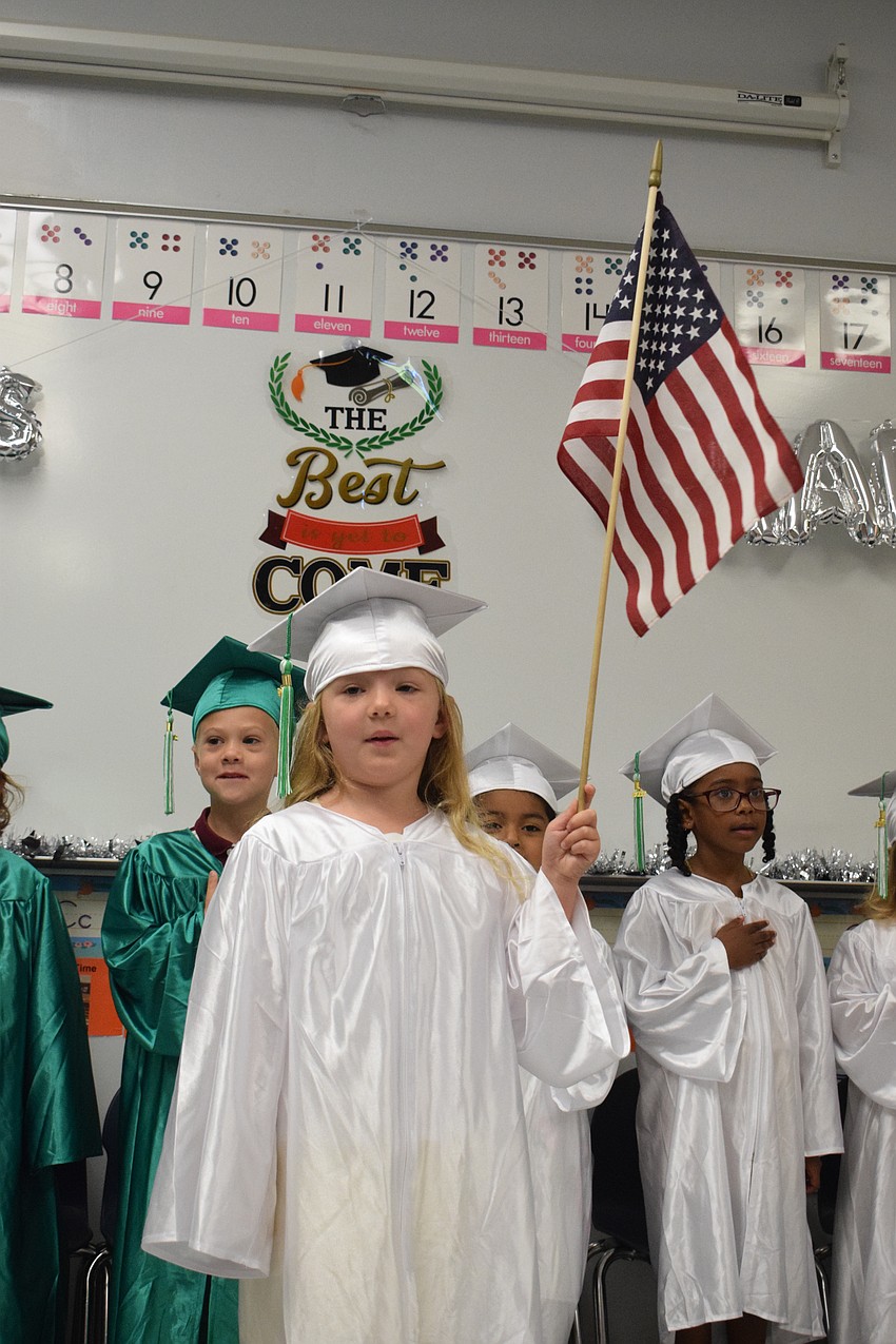 Mini Mustangs' Seraphina Michael holds the flag during the Pledge of Allegiance.