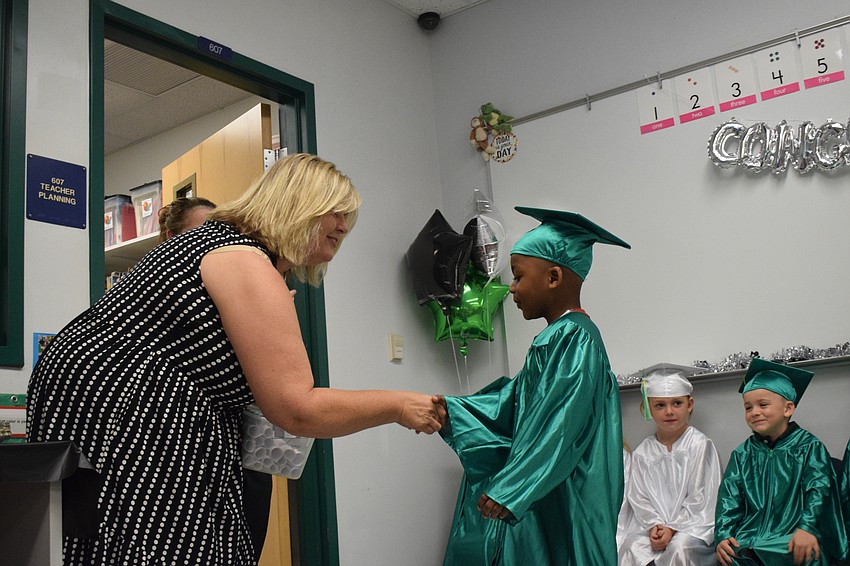 Cass Schutte, a Mini Mustangs teacher, congratulates Amir Phillips on graduating from pre-K.