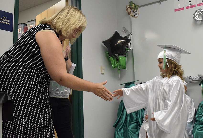 Cass Schutte, the Mini Mustangs teacher, shakes hands with Kaylie Field, a pre-K student.