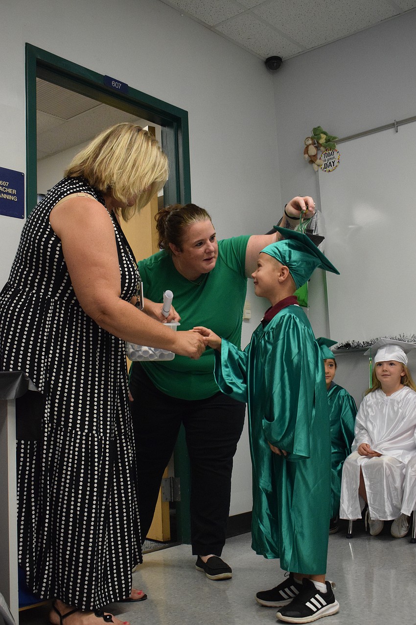 Cass Schutte, the Mini Mustangs teacher, hands Mason Gogoel his diploma as Sara Lay, Schutte's assistant, turns his tassel.
