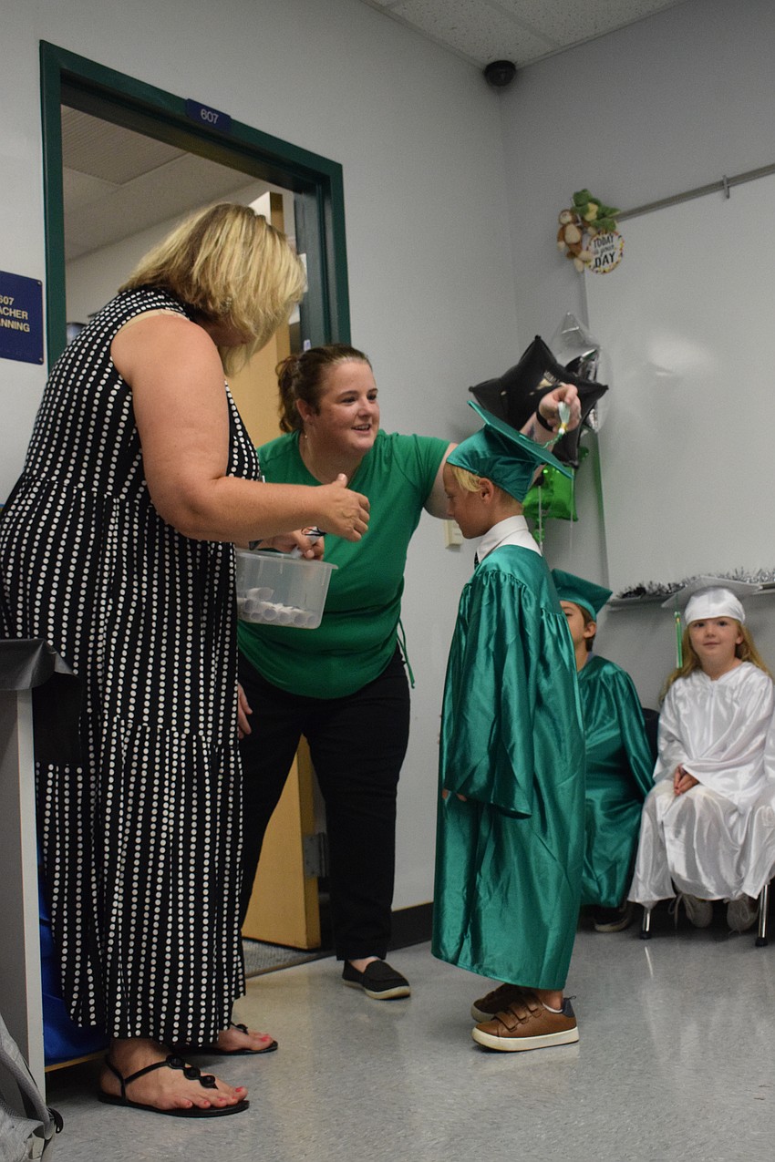 Cass Schutte, the Mini Mustangs teacher, congratulates Rowan Riedl as Sara Lay, who is Schutte's assistant, turns his tassel.