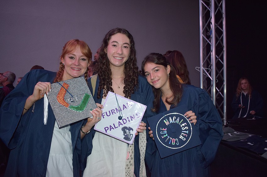 Out-of-Door Academy's Kaylee Shockey, Audrey Cochran and Ines Visa decorate their caps to reflect where they're going to college.
