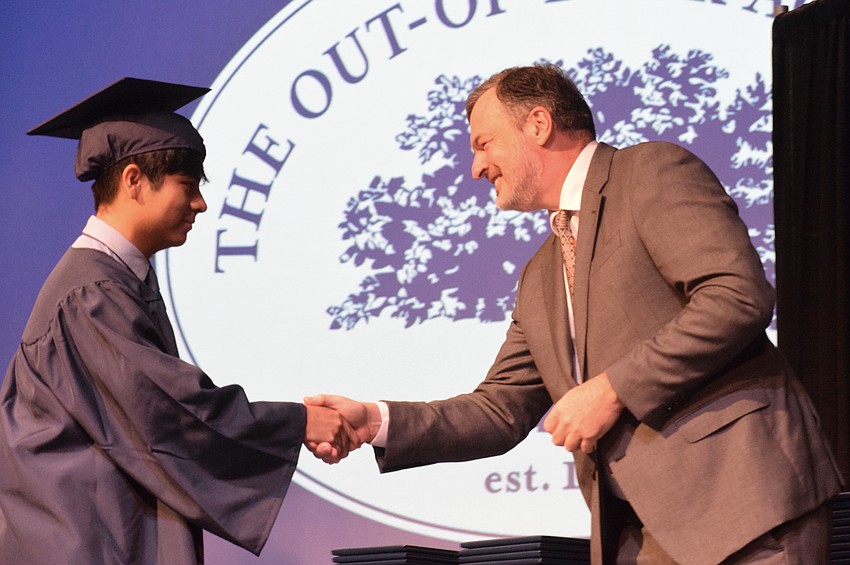 Out-of-Door Academy's Donovan Ballinas shakes hands with Thomas Murphy, the chair of ODA's board of trustees, before accepting his diploma.
