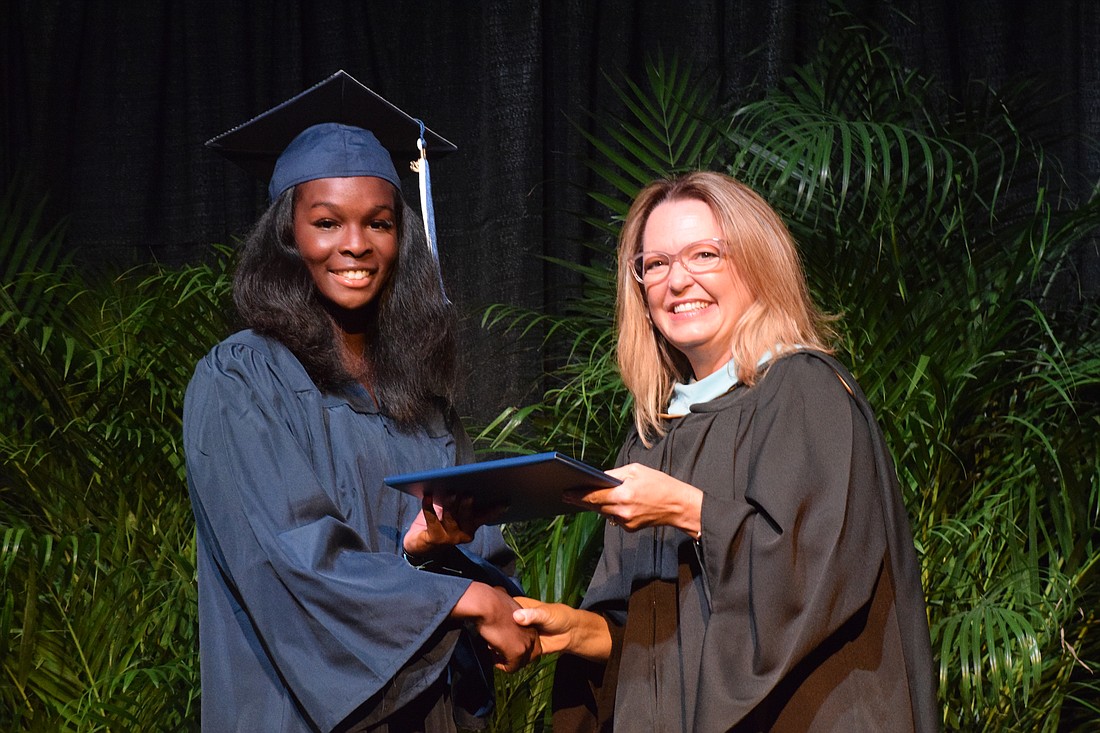 Out-of-Door Academy's Rhegan Duncombe smiles as she accepts her diploma from Deb Otey, the head of school.