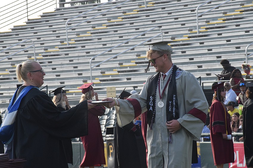 Braden River High School Assistant Principal Laura Gonzalez hands Benny Hedgepeth his diploma.