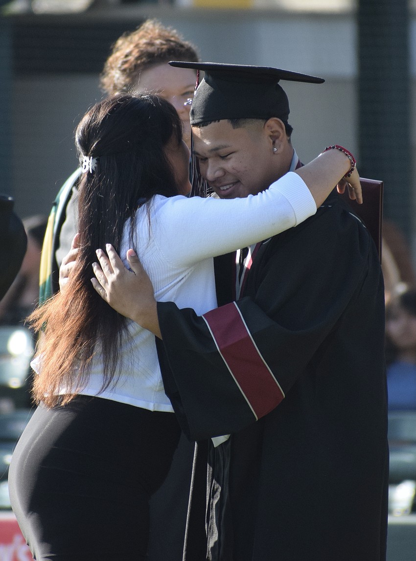 Braden River High School bookkeeper assistant Marisol Hernandez hugs her son Nathan Zapote before handing him his diploma.