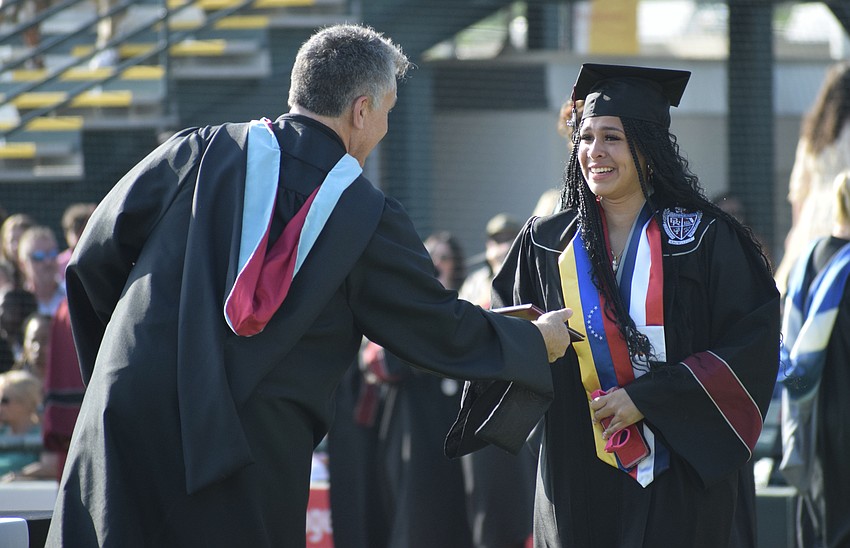 Braden River High School Assistant Principal Matthew Whelden hands Erika Vargas her diploma as she holds back tears.