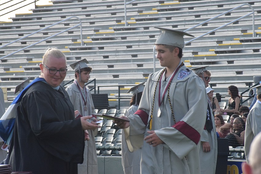 Braden River High School Assistant Principal Laura Gonzales hands Terrence Tysall his diploma.