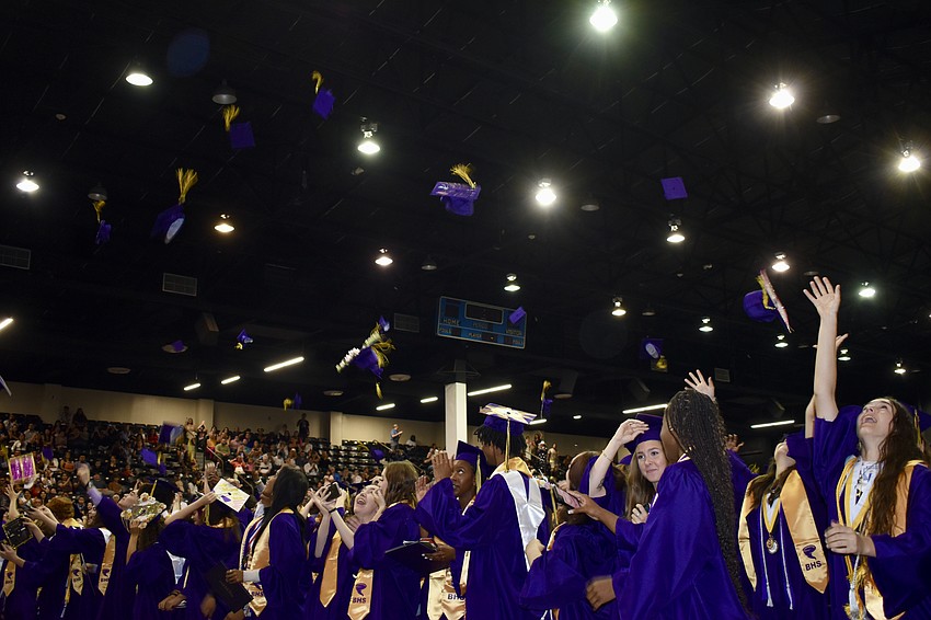 Students throw their caps as their graduation is formally announced.