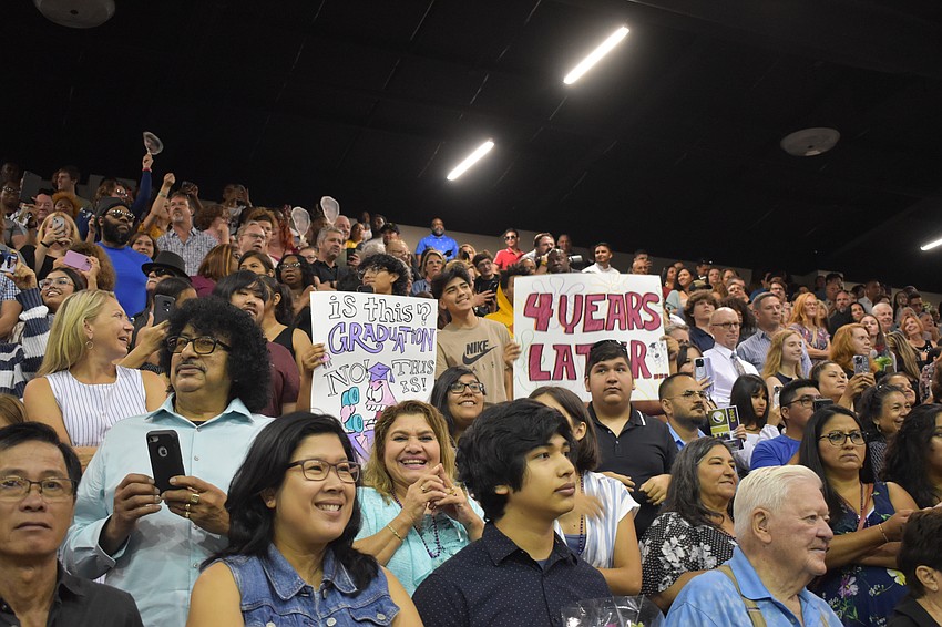Parents hold signs for graduates as the ceremony begins.