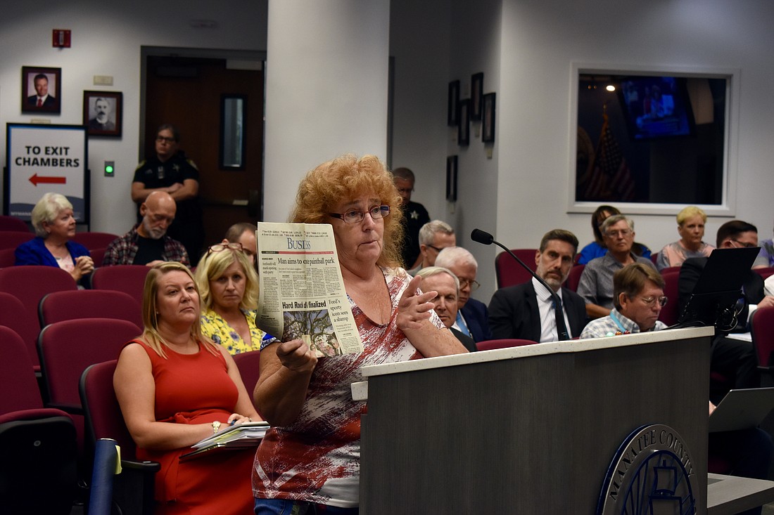 222nd Street resident Carla Tralick holds up an old newspaper article that featured her son Thomas Tralick and said today was his birthday. The proposed East River Ranch thoroughfare was originally planned through the Tralicks' backyard, where Thomas is buried.