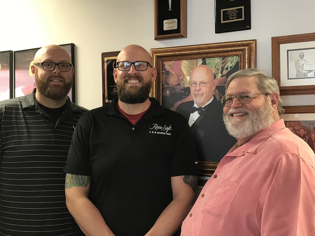 A&B Marketing Inc. Secretary Brandon Keck, President Austin Keck and General Manager Jay Toblin in front of a portrait of founder Michael Keck.