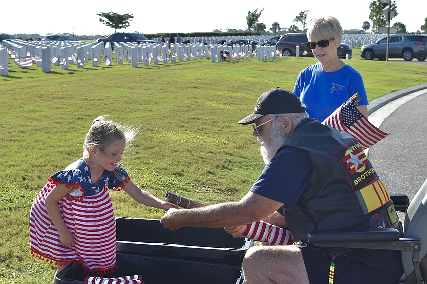 Emma Masciulli helps Jim Currie with the flags, as does Phala Amey.