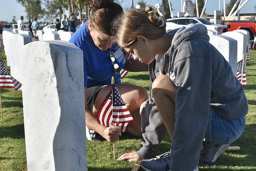 Erin Masciulli and 15-year-old Aly Miller place a flag in the ground.