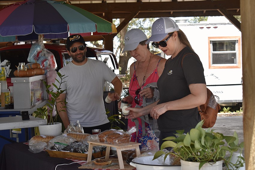 Ryan Young, Linda Schmidt and Julia Young browse the market after taking a tour of the farm. The Youngs are visiting Schmidt in Old Miakka from Los Angeles. They left the tour shaking jars of cream to churn into butter.