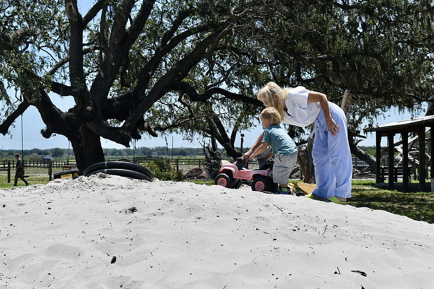 Alexander Langer gets help pushing a truck up the sand hill from grandma Jenny Blair, who lives in Nokomis.
