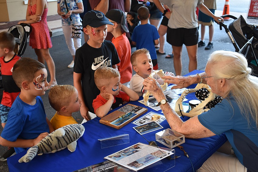 Lakewood Ranch's Ashton Nicholson, Clayton Nicholson, Leo Stace, and Preston Nicholson, and Minnesota's James Jensen learn about Mote Marine from volunteer Mary Hasselbring before the parade.