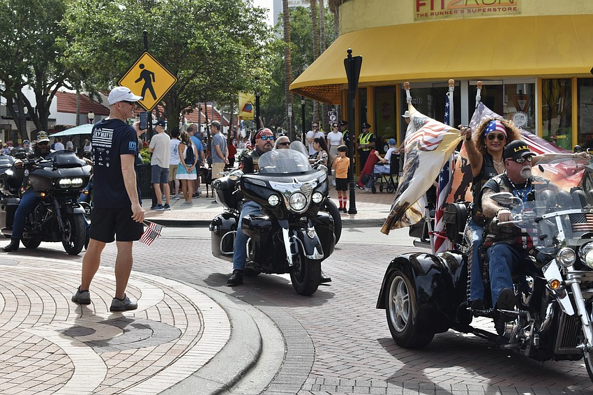 Tim Curtin waves flags at a group of motorcyclists.