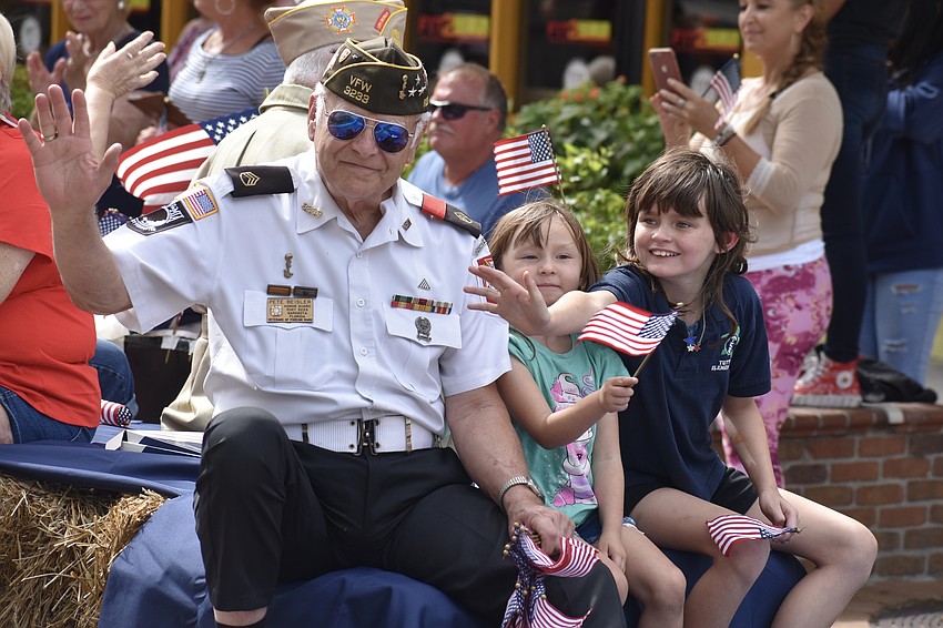 Pete Beisler of Veterans of Foreign Wars Sunshine Post 3233, and his granddaughters, 5-year-old Harlee Carll and 11-year-old Kerriana Carll, greet the crowds lining the streets.
